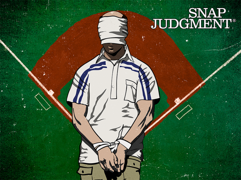 A man is blindfolded and his hands are bound. There is a baseball field behind him.