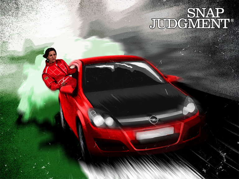 Two women are in a red race car, speeding around a corner.